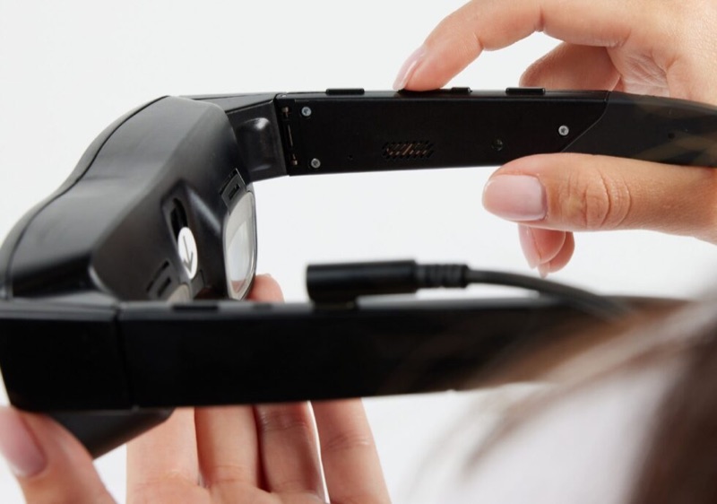 eSight Go, a black electronic headset held up to the face